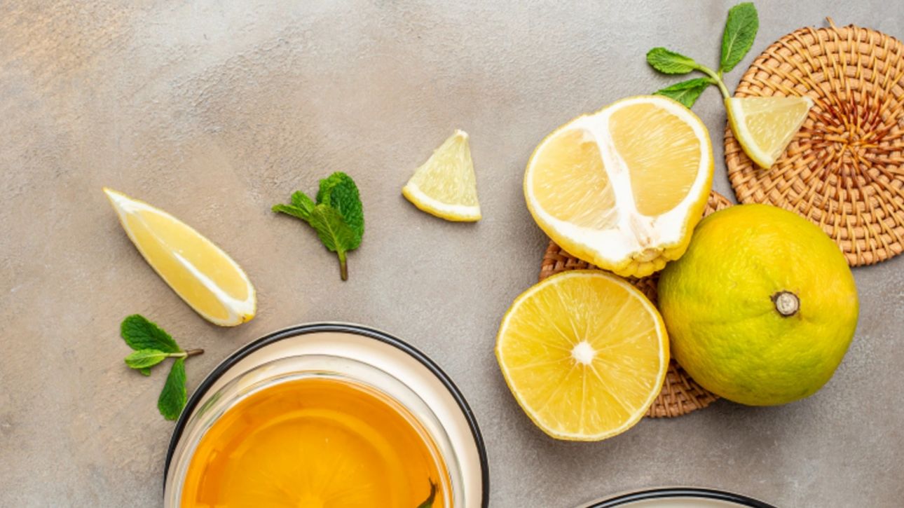 fresh bergamot fruit, a glass of bergamot juice, and mint leaves on a textured surface.