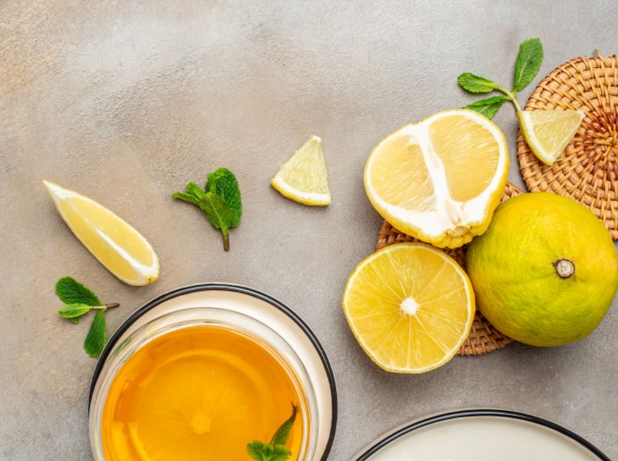 fresh bergamot fruit, a glass of bergamot juice, and mint leaves on a textured surface.